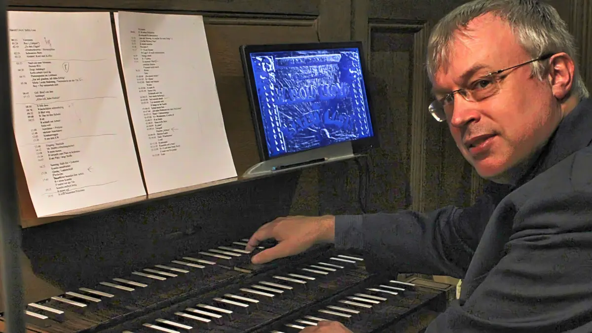 Torsten Wille hat den Ablaufplan und den Filmmonitor vor sich. Die Musik wird ohne Noten improvisiert.