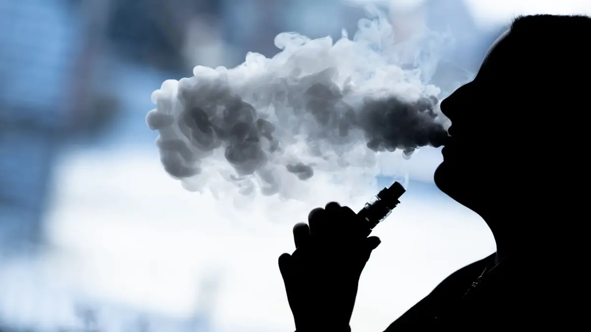 E-Zigaretten: ARCHIV - 07.02.2022, Baden-Württemberg, Bösingen: Eine junge Frau raucht mit einer E-Shisha und ist dabei als Silhouette zu sehen. Die Bundesregierung möchte 13 zentrale Inhaltsstoffe von E-Zigaretten-Liquids verbieten. (zu dpa: ««Tod der E-Zigarette»? Branche ist besorgt über Verbotspläne») Foto: Silas Stein/dpa +++ dpa-Bildfunk +++