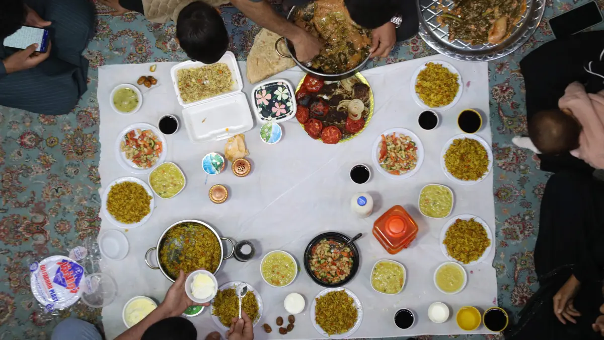 Muslim visitors and families gather for Iftar or the breaking of the dawn to dusk fast, at the shrine of Imam al-Qasim, son of Imam al-Kadhim, on the first Friday of the holy month of Ramadan, in al-Qasim, south of the city of Hilla on February 20, 2026. Muslim perform prayers and participate in supplication sessions, while dates, water, food are distributed on the second day of the holy month of Ramadan, during which believers fast for the 30 days of Ramadan. (Photo by Karar Jabbar / AFP)
