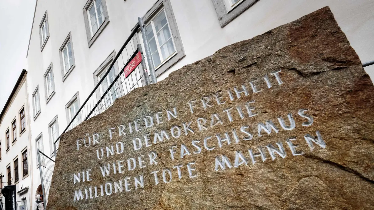 Picture taken on February 17, 2026 shows a memorial stone reading "For Peace, Freedom and Democracy - Never Again Fascism - Millions of Dead Warn" in front of the birth house of former German dictator Adolf Hitler that is turned into a police station, in Braunau am Inn, Austria. The controversial redesign of the house in the northern Austrian town of Braunau started in 2023. Following years of legal wrangling, the government took control of the dilapidated building in 2016 and decided to turn the house, where Hitler was born in 1889, into a police station. (Photo by Joe Klamar / AFP)