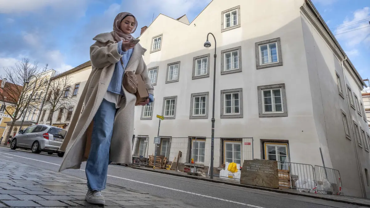 A woman walks past the birth house of former German dictator Adolf Hitler that is turned into a police station, in Braunau am Inn, Austria, on February 17, 2026. The controversial redesign of the house in the northern Austrian town of Braunau started in 2023. Following years of legal wrangling, the government took control of the dilapidated building in 2016 and decided to turn the house, where Hitler was born in 1889, into a police station. (Photo by Joe Klamar / AFP)