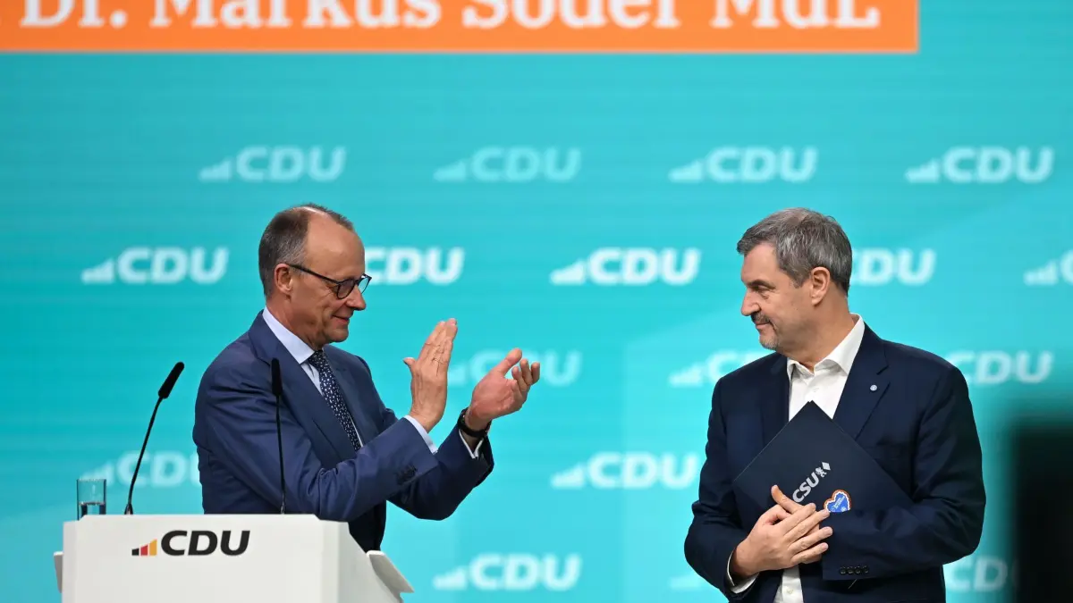 CDU-Bundesparteitag: 21.02.2026, Baden-Württemberg, Stuttgart: Bundeskanzler Friedrich Merz (l, CDU) und Markus Söder, CSU-Vorsitzender und Ministerpräsident von Bayern, stehen beim CDU-Bundesparteitag auf der Bühne. Nach den Vorstandswahlen geht es am zweiten Tag des Parteitags um die Inhalte. Unter anderem stehen Anträge zu Teilzeit, Einschränkung der Social-Media-Nutzung für Kinder und zur Rentenreform zur Beratung an. Foto: Katharina Kausche/dpa +++ dpa-Bildfunk +++