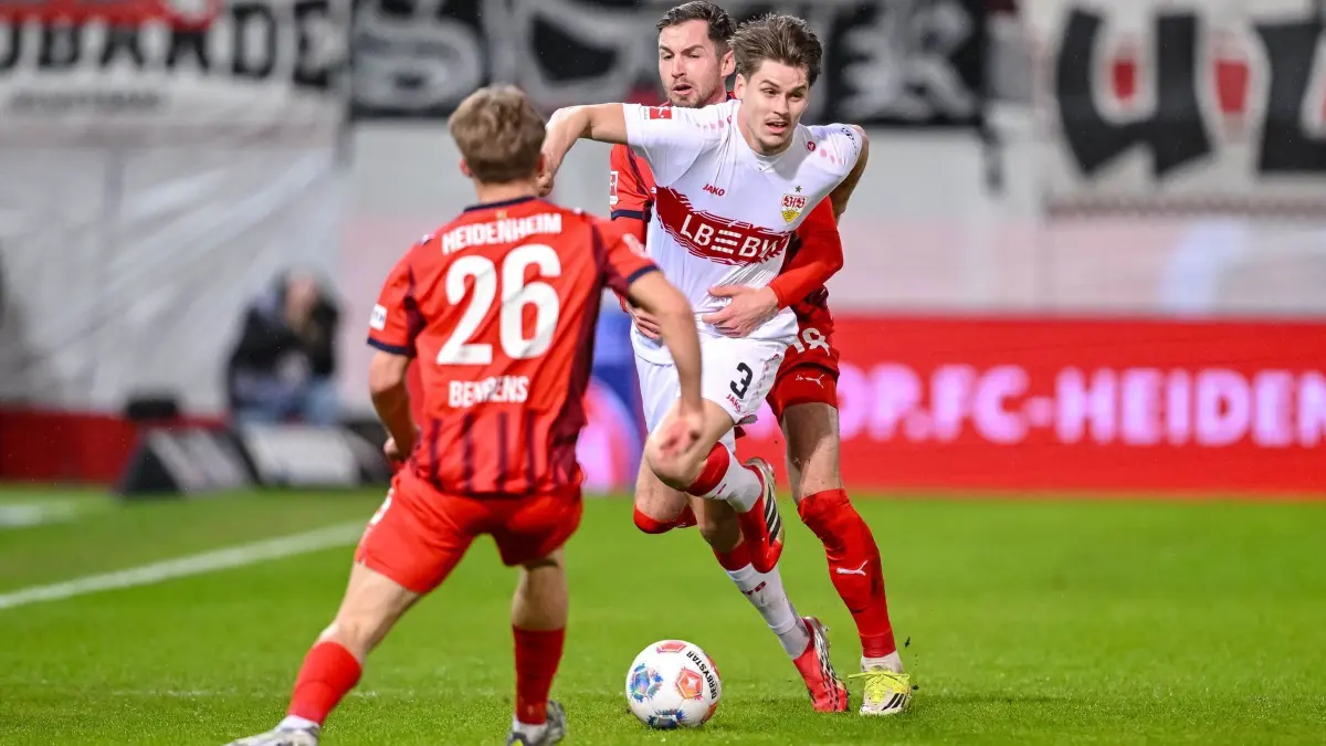 1. FC Heidenheim - VfB Stuttgart: 22.02.2026, Baden-Württemberg, Heidenheim: Fußball, Männer, Bundesliga, 23. Spieltag, 1. FC Heidenheim - VfB Stuttgart, Voith-Arena: Hennes Behrens (l, 1. FC Heidenheim 1846) in Aktion gegen Ramon Hendriks (VfB Stuttgart) und Marvin Pieringer (1. FC Heidenheim 1846). Foto: Harry Langer/dpa - WICHTIGER HINWEIS: Gemäß den Vorgaben der DFL Deutsche Fußball Liga bzw. des DFB Deutscher Fußball-Bund ist es untersagt, in dem Stadion und/oder vom Spiel angefertigte Fotoaufnahmen in Form von Sequenzbildern und/oder videoähnlichen Fotostrecken zu verwerten bzw. verwerten zu lassen. +++ dpa-Bildfunk +++