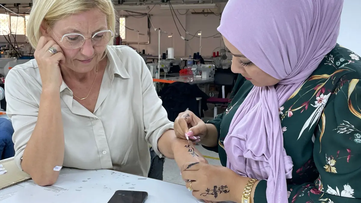 Kultur hautnah erleben: Eine Tunesierin bemalt die Hand von Ute Beck mit Henna. Die Arbeiterinnen haben sich nach Feierabend zusammengesetzt, um sich gegenseitig zu bemalen. Die Körperbemalung mit Henna ist eine jahrtausendealte Tradition.