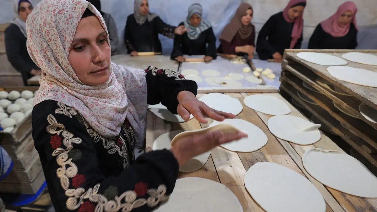 Palestinian women prepare bread for distribution to families in need at the Bureij camp for the displaced during the Muslim holy fasting month of Ramadan, on February 23, 2026. (Photo by Eyad Baba / AFP)