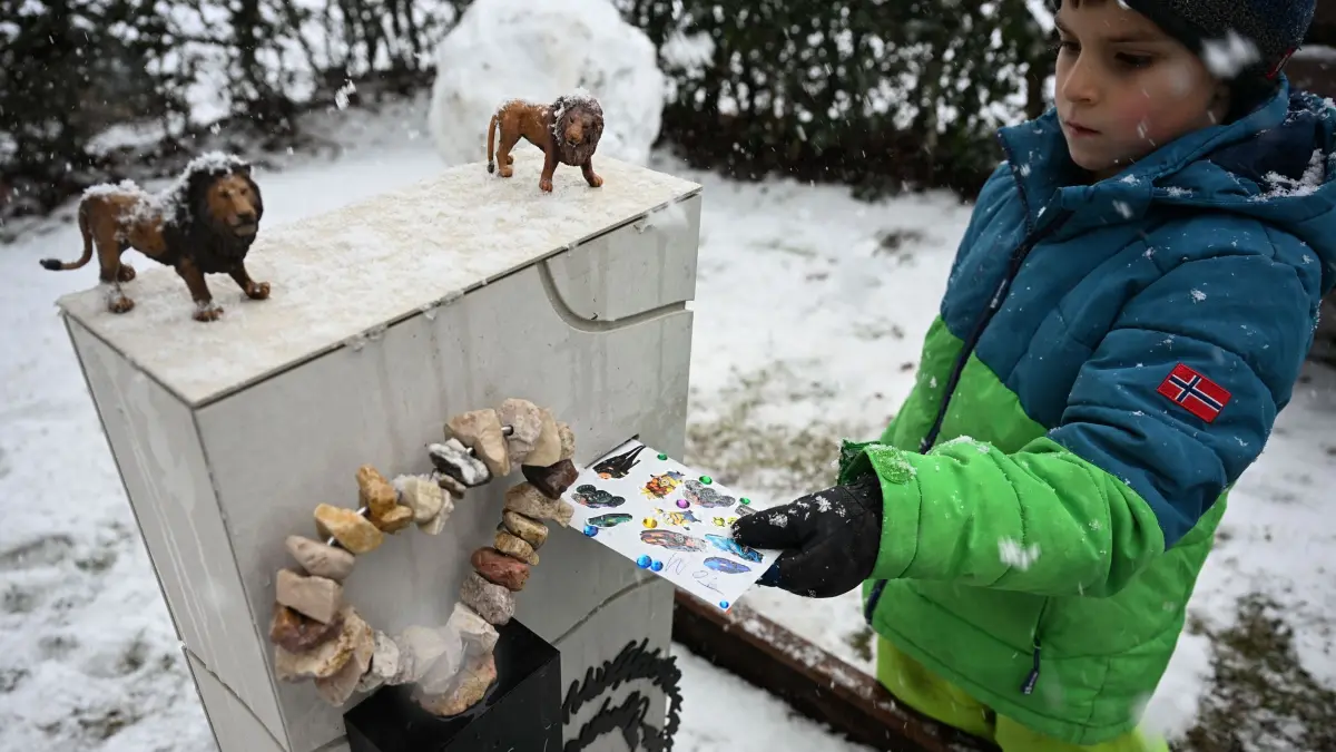 Grabsteine mit Briefschlitz: PRODUKTION - 17.02.2026, Baden-Württemberg, Bad Wildbad: Tom wirft einen Brief für seinen Vater in den Briefschlitz an seinem Grabstein. Der Familienvater starb 2023 an Krebs. Auf seinem Grab steht ein Grabstein mit Briefschlitz, in den die Familie Briefe einwerfen kann. Foto: Katharina Kausche/dpa - ACHTUNG: Nur zur redaktionellen Verwendung im Zusammenhang mit der aktuellen Berichterstattung und nur mit vollständiger Nennung des vorstehenden Credits +++ dpa-Bildfunk +++