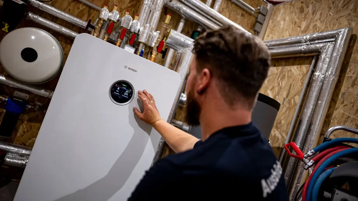 Handwerker zeigt an einer Wärmepumpe auf die Anzeige: ARCHIV - Wer eine alte Gas- oder Ölheizung gegen eine moderne Alternative tauscht, kann noch immer von einer staatlichen Förderung profitieren. (zu dpa: «Heizungstausch geplant? Schnell sein kann sich lohnen») Foto: Fabian Sommer/dpa/dpa-mag - Honorarfrei nur für Bezieher des Dienstes dpa-Magazin +++ dpa-Magazin +++
