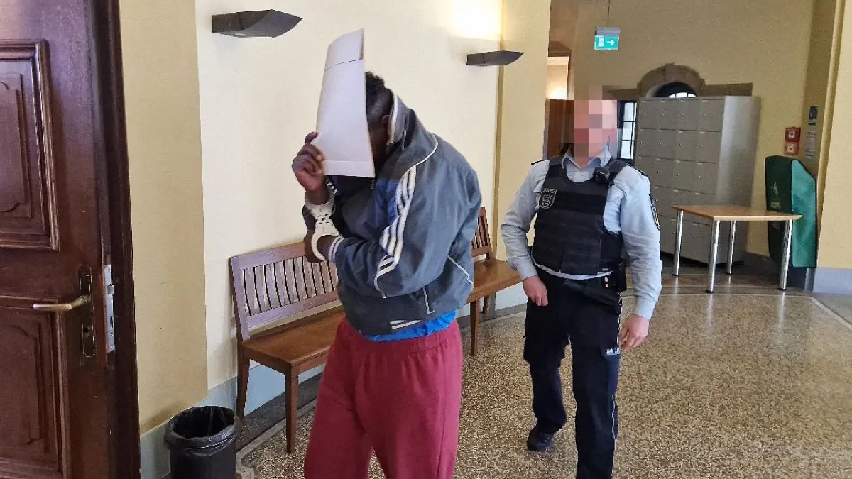 Der Angeklagte wird in Begleitung eines Polizisten in den Gerichtssaal gebracht.