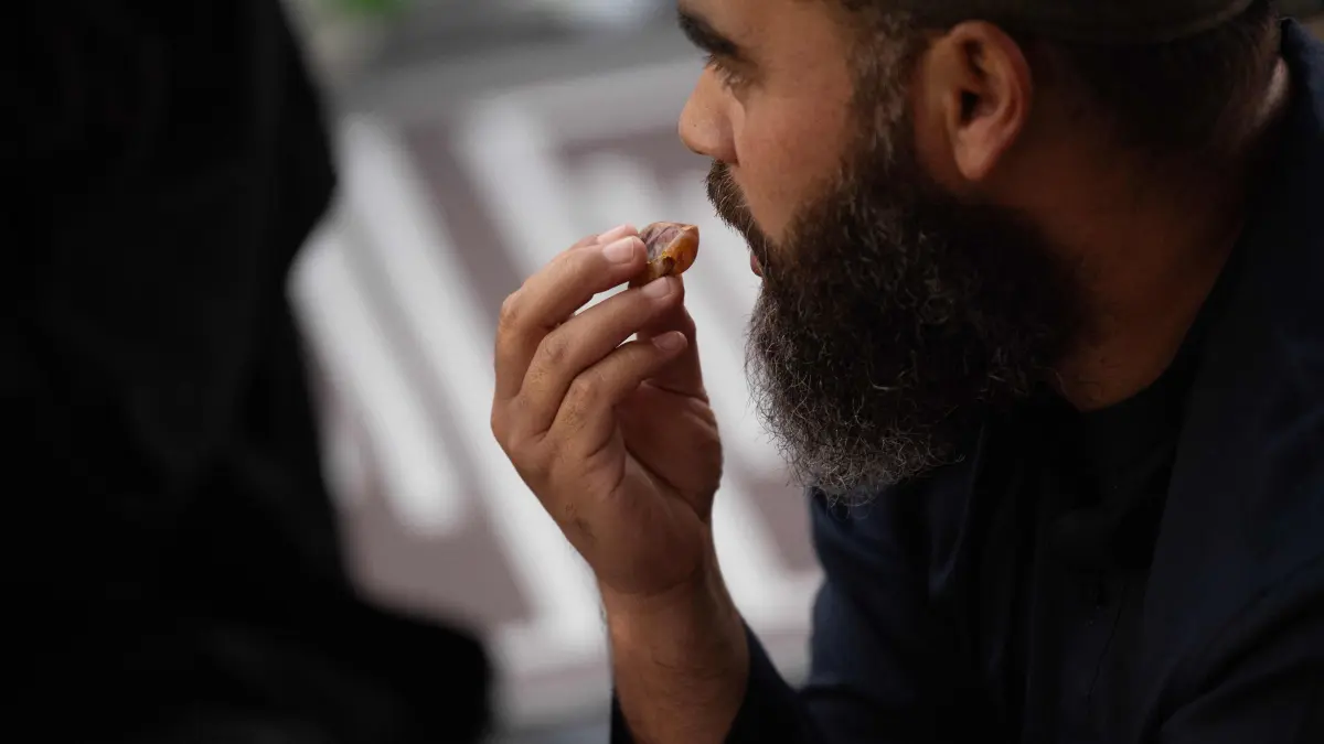 A man eats a date, joining thousands of Muslims as they break their daily fast at a Mass Iftar event in the Bo Kaap, the city’s oldest Muslim settlement, in Cape Town on February 27, 2026. (Photo by RODGER BOSCH / AFP)