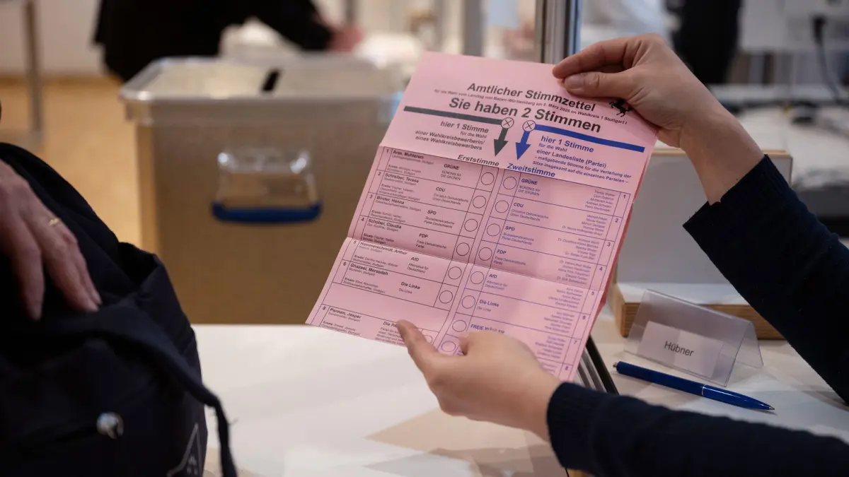 Landtagswahl in Baden-Württemberg - Briefwahl: PRODUKTION - 11.02.2026, Baden-Württemberg, Stuttgart: Eine Wahlhelferin zeigt im Rathaus einer Briefwählerin einen Stimmzettel zur baden-württembergischen Landtagswahl 2026. (zu dpa: «Diese 21 Parteien treten zur Landtagswahl an») Foto: Marijan Murat/dpa +++ dpa-Bildfunk +++
