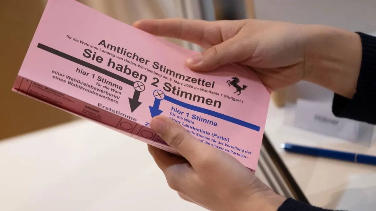 Landtagswahl 2026 in Baden-Württemberg - Briefwahl: PRODUKTION - 11.02.2026, Baden-Württemberg, Stuttgart: Eine Wahlhelferin zeigt im Rathaus einer Briefwählerin einen Stimmzettel zur baden-württembergischen Landtagswahl 2026. (zu dpa: «Das hat es mit dem neuen Wahlrecht im Südwesten auf sich») Foto: Marijan Murat/dpa +++ dpa-Bildfunk +++