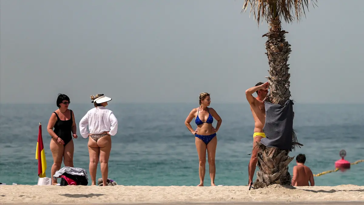 People stand at the beach in Dubai's Jumeirah area on March 2, 2026. Iran's strikes on Gulf neighbours since February 28, following the US-Israeli attack, forced the UAE to shut its airspace, blindsiding travellers who thought they were headed to one of the region's safest holiday destinations. (Photo by Fadel SENNA / AFP)
