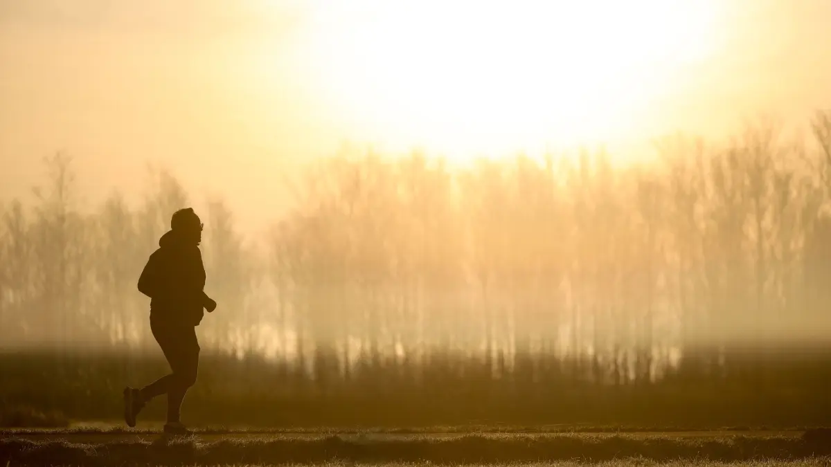 Wetter in Baden-Württemberg: ARCHIV - 21.03.2025, Baden-Württemberg, Moosburg: Ein Jogger ist am Morgen im Gegenlicht der Sonne unterwegs, während sich der Himmel durch Saharastaub gelb verfärbt hat. (zu dpa: «Saharastaub im Südwesten») Foto: Thomas Warnack/dpa +++ dpa-Bildfunk +++