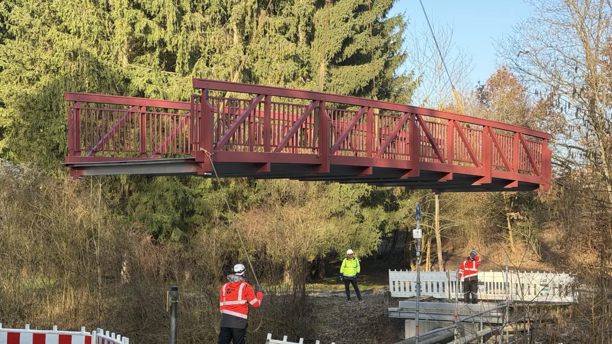 Langsam schwebt die neue Brücke auf die Fundamente. Das Fertigteil aus Aluminium ersetzt die alte Holzbrücke über die Starzel. Der Fuß- und Radweg wird in zwei bis drei Wochen wieder befahrbar sein.