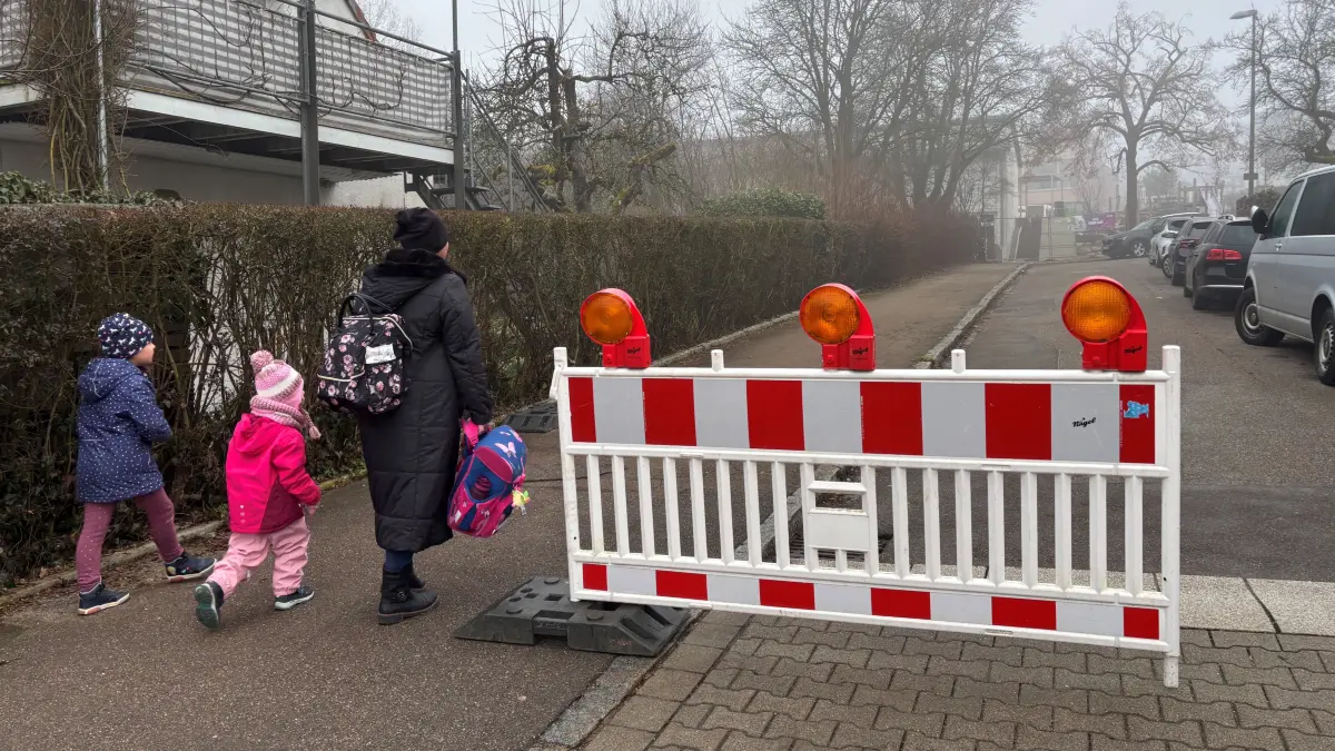 Vierte Schulstraße in Ulm an der Jörg-Syrlin-Schule am Kuhberg: Am unteren Ende des Märchenwegs stellt in den ersten beiden Wochen jeweils ein Security-Mitarbeider eine Schranke auf, um den Elterntaxis die Zufahrt zu verwehren. Eine Mutter bringt ihre Kinder zu Fuß zur Schule.