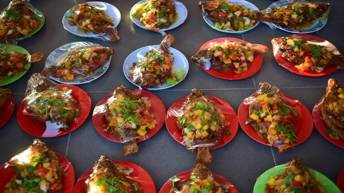 Fried sweet and sour fish are seen under cling wrap ahead of the breaking of fast during the holy month of Ramadan at the Darul Iman Orphanage in Ban Sapom, in the southern Thai province of Narathiwat on March 7, 2026. (Photo by Madaree TOHLALA / AFP)