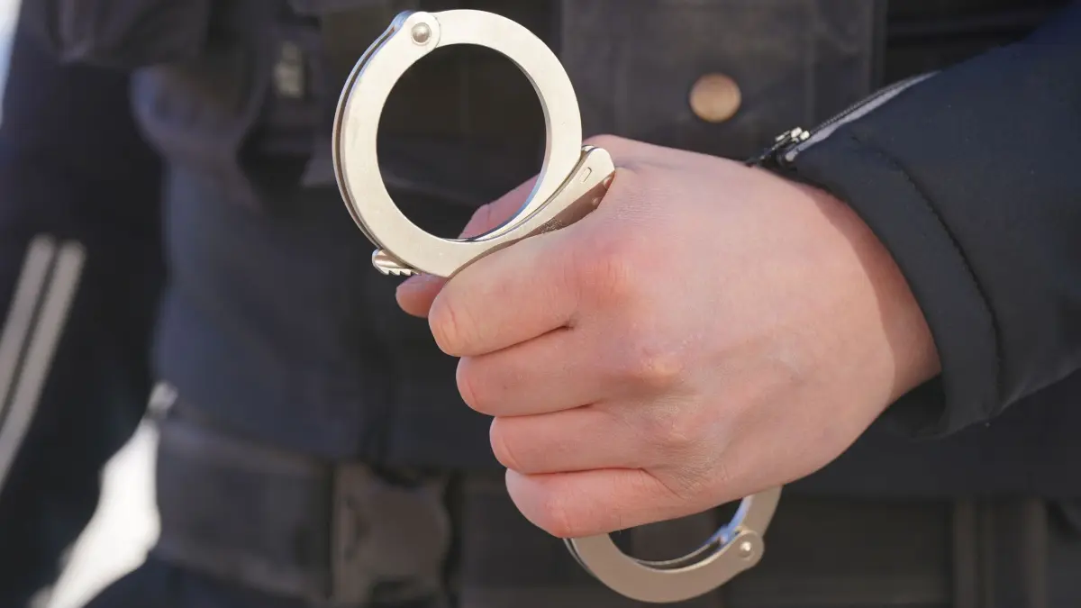 Polizei Handschellen: ARCHIV - 18.01.2024, Mecklenburg-Vorpommern, Schwerin: Ein Polizist hält Handschellen in der Hand. (zu dpa: «Dutzende Straftaten - 15-Jähriger verhaftet») Foto: Marcus Brandt/dpa +++ dpa-Bildfunk +++