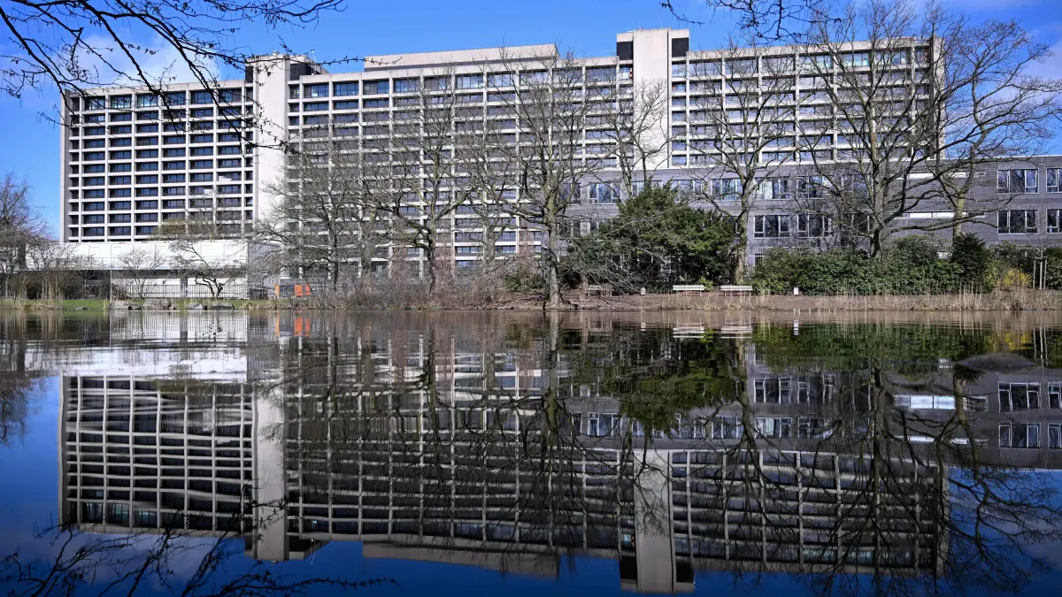 The Deutsche Bundesbank's historic 1970s building is reflected in the water in Frankfurt am Main, western Germany, on March 12, 2026. Germany's central bank said on March 11, 2026 it was abandoning a project to renovate its historic Frankfurt headquarters after furious criticism over costs that could spiral into the billions, and would instead move permanently to a new site. The enormous 1970s brutalist concrete building had become synonymous with the Bundesbank and was said to reflect its culture of fostering economic stability. The planned overhaul envisaged adding new buildings to create a campus. Some 170 million euros ($196 million) had already been spent, including on removing asbestos, and the bank had relocated temporarily to different offices in downtown Frankfurt. (Photo by Kirill KUDRYAVTSEV / AFP)