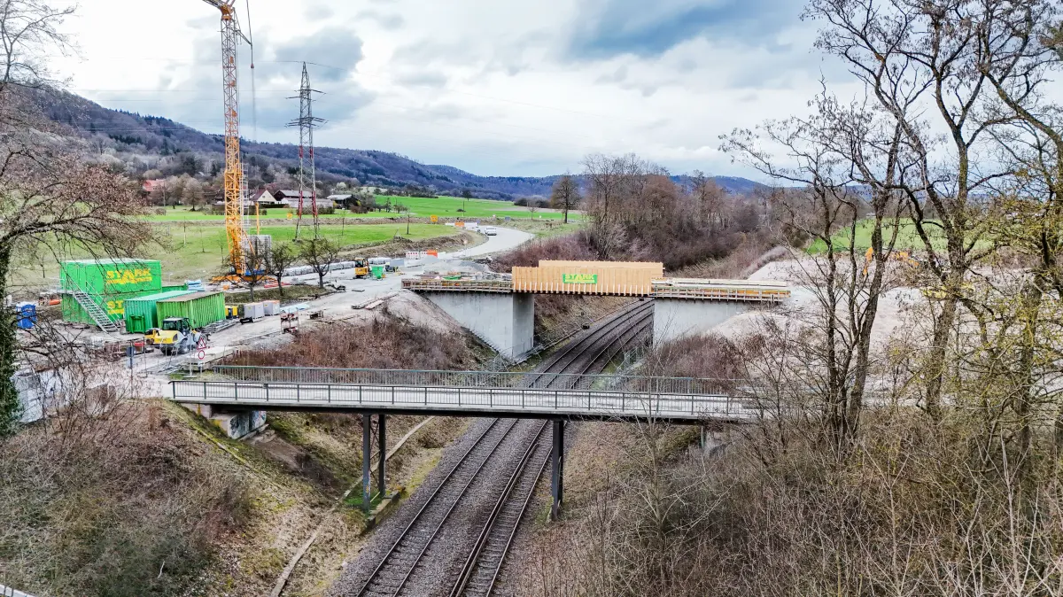 Der Brückenneubau über die Bahn bei Gottwollshausen schreitet planmäßig voran. Nach der „Brückenhochzeit“, dem Einhub der Fertigteile von beiden Seiten im November des vergangenen Jahres, kann nun auch mit den erforderlichen Straßenbauarbeiten und dem Abbruch der alten Brücke begonnen werden. Hierzu sind die Vollsperrung der Brunnenteichstraße bis zur Westumgehung, und der Kreisstraße K2577 über die alte Brücke bis Sülz erforderlich. - Brücke wird abgerissen