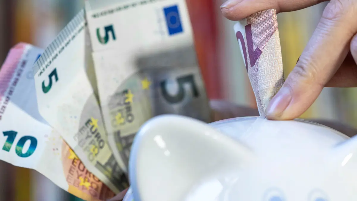 Sparen: ILLUSTRATION - 23.10.2023, Sachsen, Leipzig: ILLUSTRATION - Eine Frau steckt einen 10 Euroschein in ein Sparschwein. Die Bremer CDU-Fraktion fordert einen Sparkurs - und andere Schwerpunkte. (zu dpa: «Sicherheit, Sprache und Sparen - Was die Bremer CDU fordert») Foto: Hendrik Schmidt/dpa +++ dpa-Bildfunk +++
