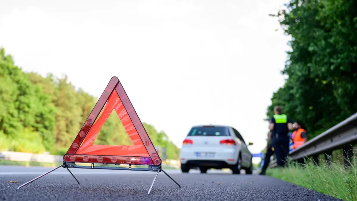 Ein Warndreieck vor einem liegengebliebenen Fahrzeug: ARCHIV - Streit nach Reifenplatzer: Ein Betroffener will den Schaden von der Versicherung ersetzt bekommen - doch die zahlt nicht. Es geht vor Gericht. (zu dpa: «Reifen geplatzt? Wann die Vollkasko nicht zahlt») Foto: Philipp Schulze/dpa/dpa-mag - Honorarfrei nur für Bezieher des Dienstes dpa-Magazin +++ dpa-Magazin +++