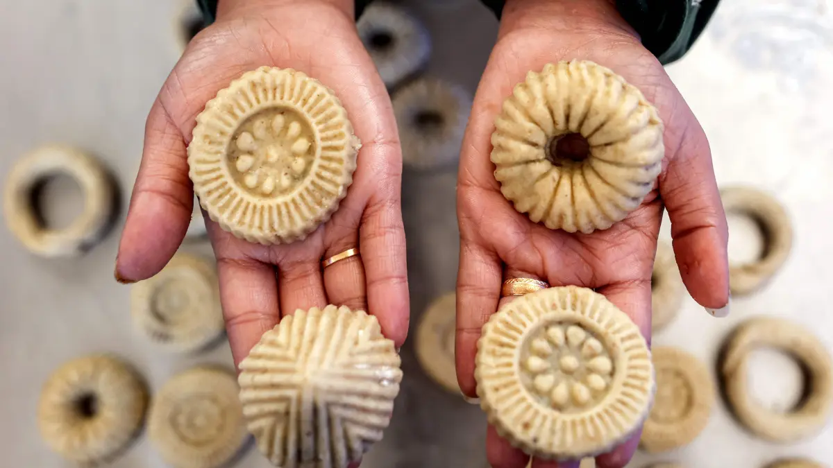 A woman holds in her hands freshly-prepared biscuits being made ahead of Eid al-Fitr, the holiday marking the end of the Muslim holy fasting month of Ramadan, in Gaza City on March 16, 2026. (Photo by Omar AL-QATTAA / AFP)