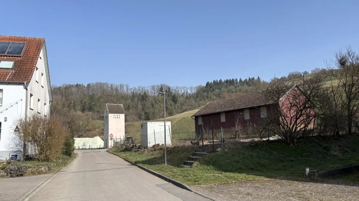An der Straße An der Bühler in Eschenau plant das Paar den Neubau eines Einfamilienhauses mit Doppelgarage, und zwar rechter Hand vor einem Wirtschaftsgebäude. Linker Hand der Straße stehen mehrere Häuser.