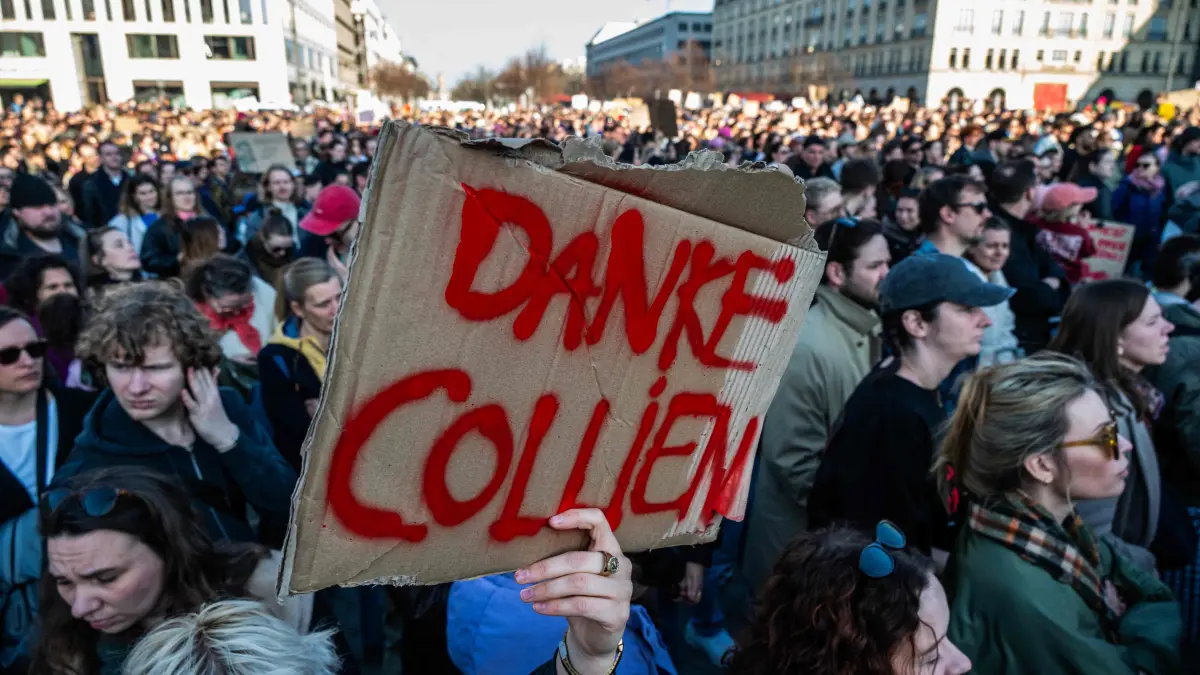 A protester holds up a placard reading "Thank you Collien" during a demonstration organised by the action group "Feminist Fight Club" on March 22, 2026 at the Brandenburg Gate in Berlin, in support of a prominent TV personality who accused her ex-husband of spreading AI-generated pornographic images of her online. The charges brought by German actress and tv presenter Collien Fernandes have triggered intense media debate about the "digital violence" increasingly perpetrated mostly against women, on the internet. (Photo by John MACDOUGALL / AFP)