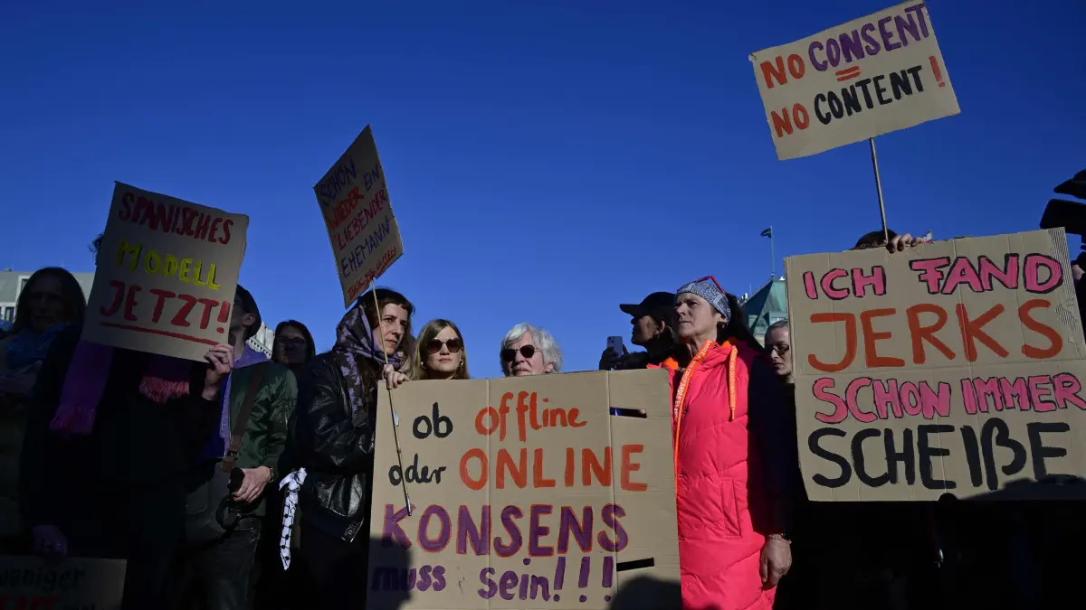 Women hold up placards as they take part in a demonstration organised by the action group "Feminist Fight Club" on March 22, 2026 at the Brandenburg Gate in Berlin, in support of a prominent TV personality who accused her ex-husband of spreading AI-generated pornographic images of her online. The charges brought by German actress and tv presenter Collien Fernandes have triggered intense media debate about the "digital violence" increasingly perpetrated against on the internet, mostly against women. (Photo by John MACDOUGALL / AFP)
