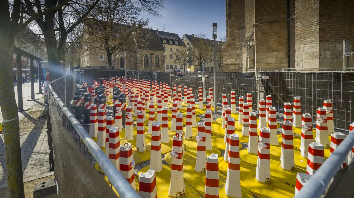 Sicherheitspollern, die hinter dem Münster eingezäunt sind und dort gelagert werden, verborgen hinter schwarzer Folie