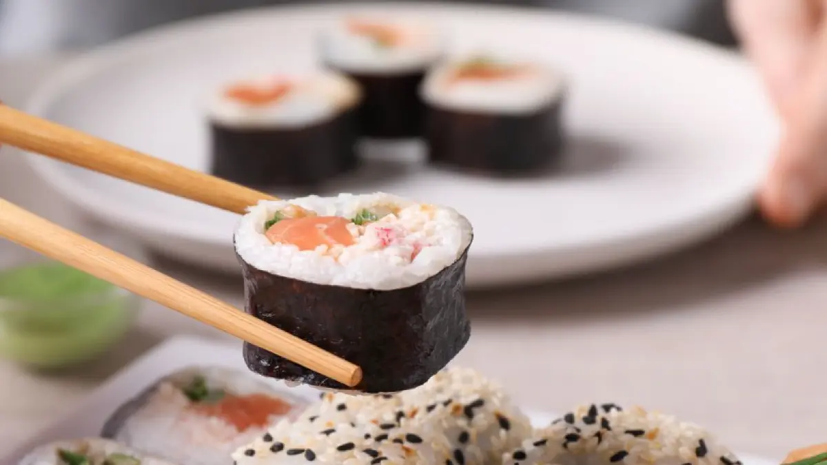 Menschen sitzen beim Essen zusammen. Sushi wird auf Tellern serviert.