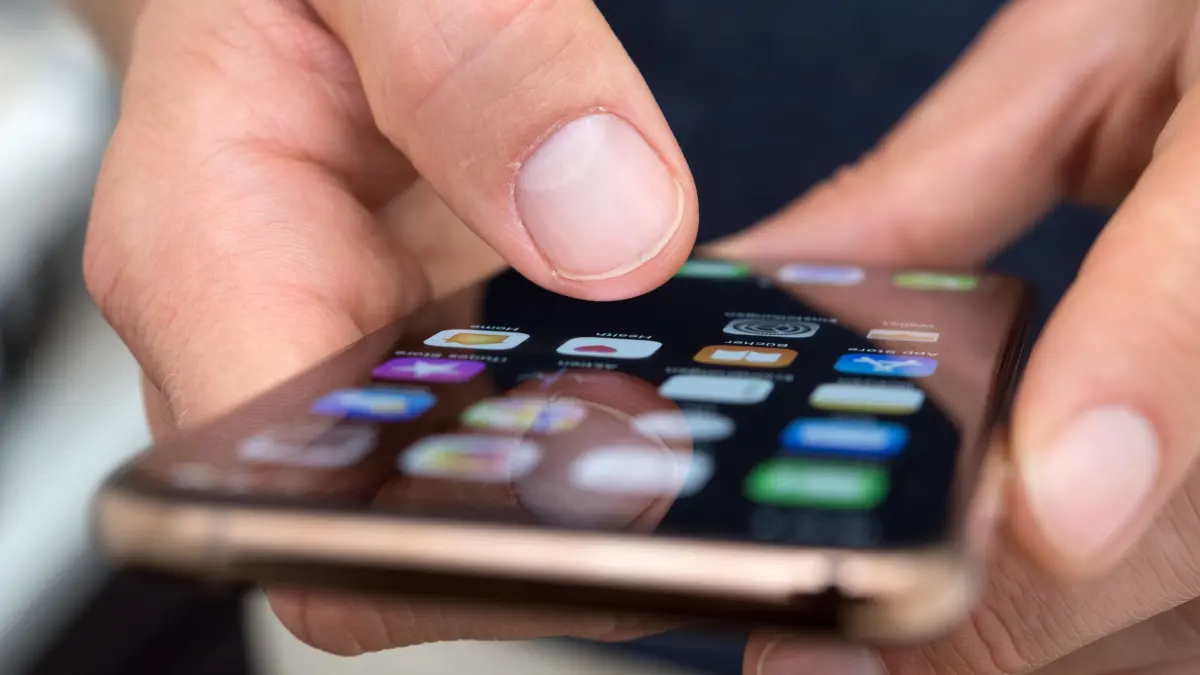 Ein Mann benutzt ein iPhone: ILLUSTRATION - Wer noch iOS 18.4 bis 18.7 nutzt, ist durch die Malware «Darksword» gefährdet. Doch auch ältere iPhones lassen sich mit einem Update schützen. (zu dpa: «So schützen Sie Ihr iPhone - vor der neuen Malware Darksword») Foto: Andrea Warnecke/dpa-mag - Honorarfrei nur für Bezieher des Dienstes dpa-Magazin +++ dpa-Magazin +++