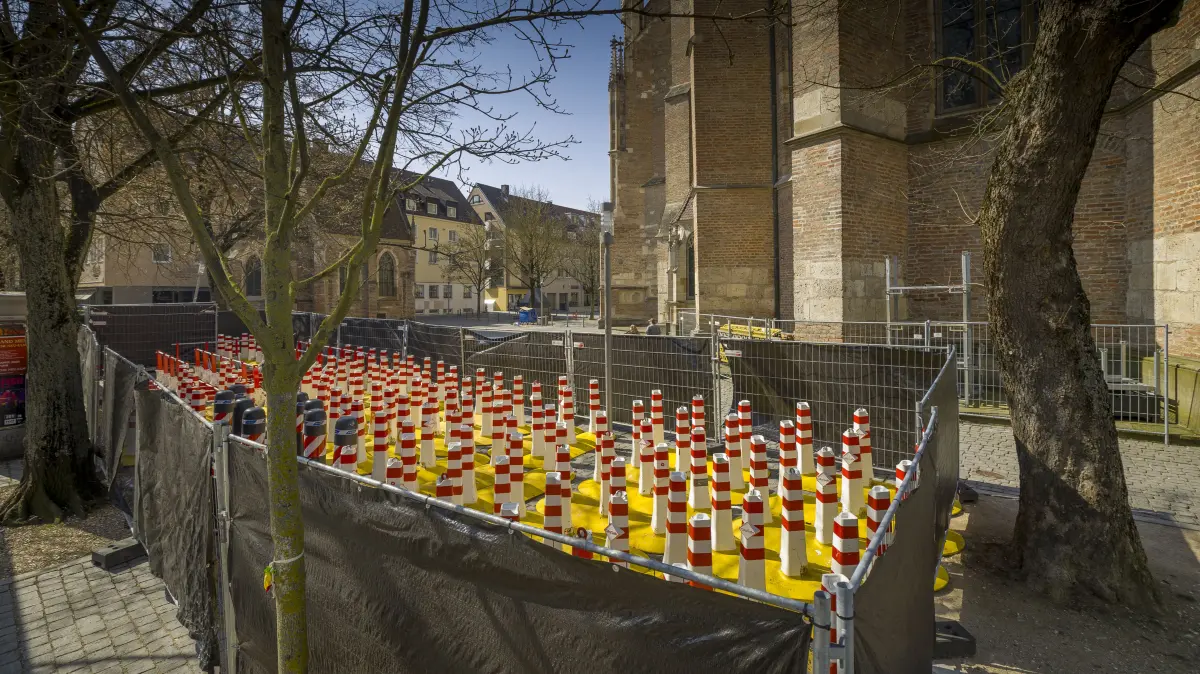 Sicherheitspollern, die hinter dem Münster eingezäunt sind und dort gelagert werden, verborgen hinter schwarzer Folie