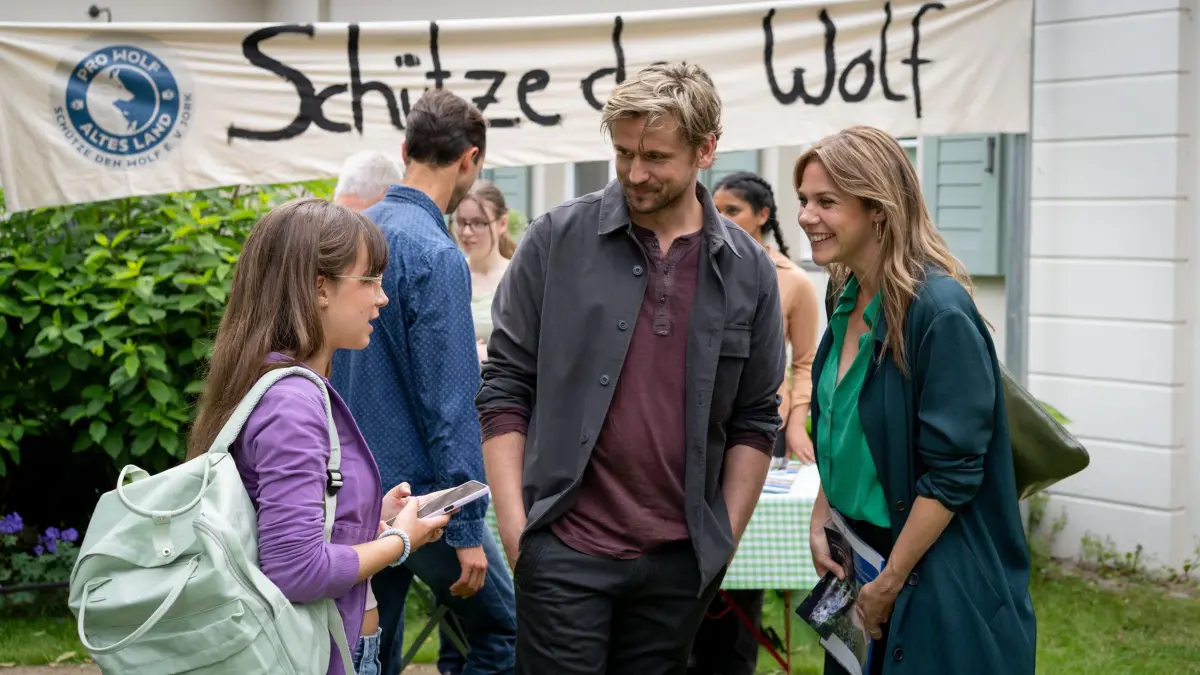 Laila (Elsa Krieger, l.) soll sich ihren Ängsten stellen und kommt mit ihrem Vater Paul (Steve Windolf, M.) zur Info-Veranstaltung der Jorker zum Streitthema "Der Wolf". Dort treffen sie auf Beke (Felicitas Woll, r.), die einen Artikel für die "Altländer Zeitung" schreibt.