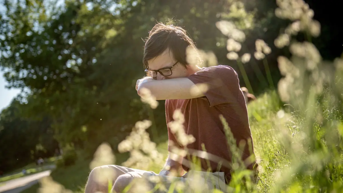 Mann in einem Park niest