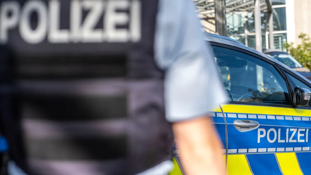 Symbolbild - Blaulicht: ILLUSTRATION - 28.09.2021, Nordrhein-Westfalen, Gütersloh: Ein Polizist steht vor einem Streifenwagen. (zu dpa: «Radfahrer bei Zusammenstoß mit Straßenbahn schwer verletzt») Foto: David Inderlied/dpa +++ dpa-Bildfunk +++