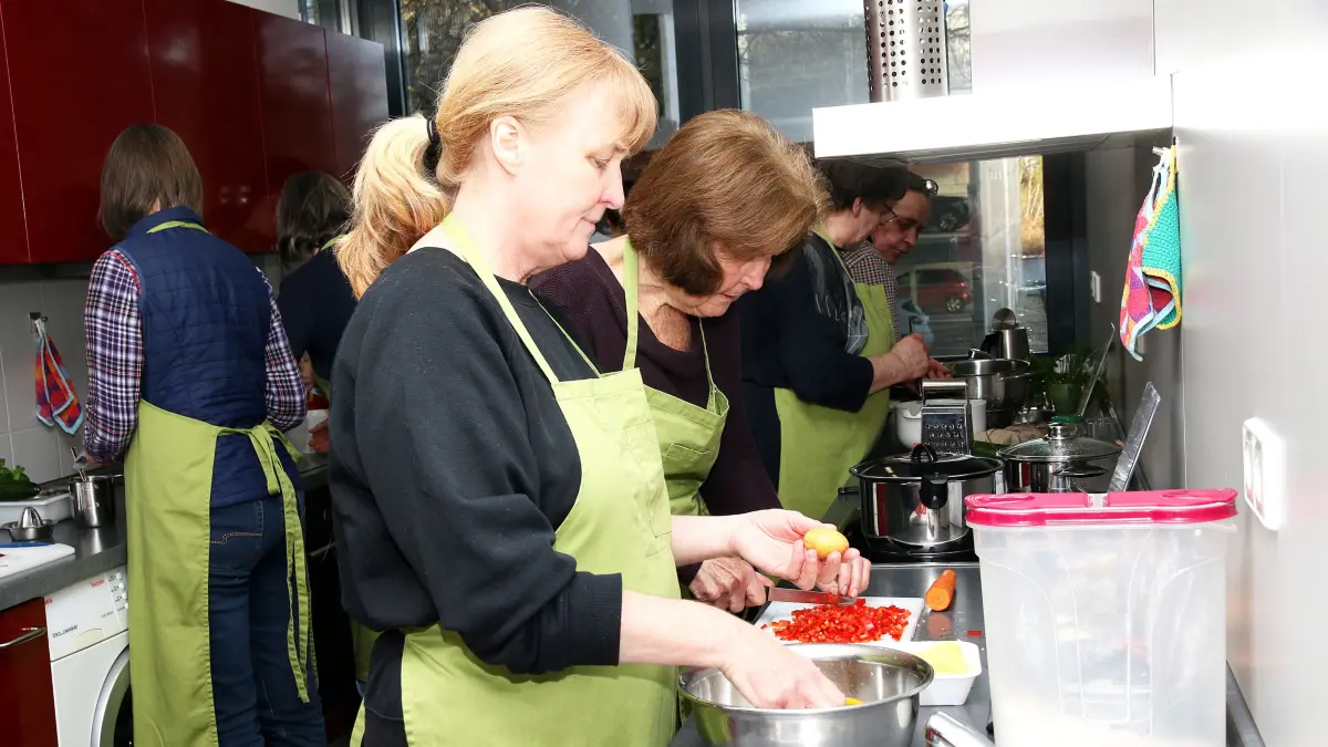 Audience Genussmenschen: Vegetarische Frühlingsküche im Landwirtschaftsamt Göppingen. Die beiden Teilnehmerinnen im Vordergrund schnippeln Paprika und Kartoffeln für die Gemüsepuffer.