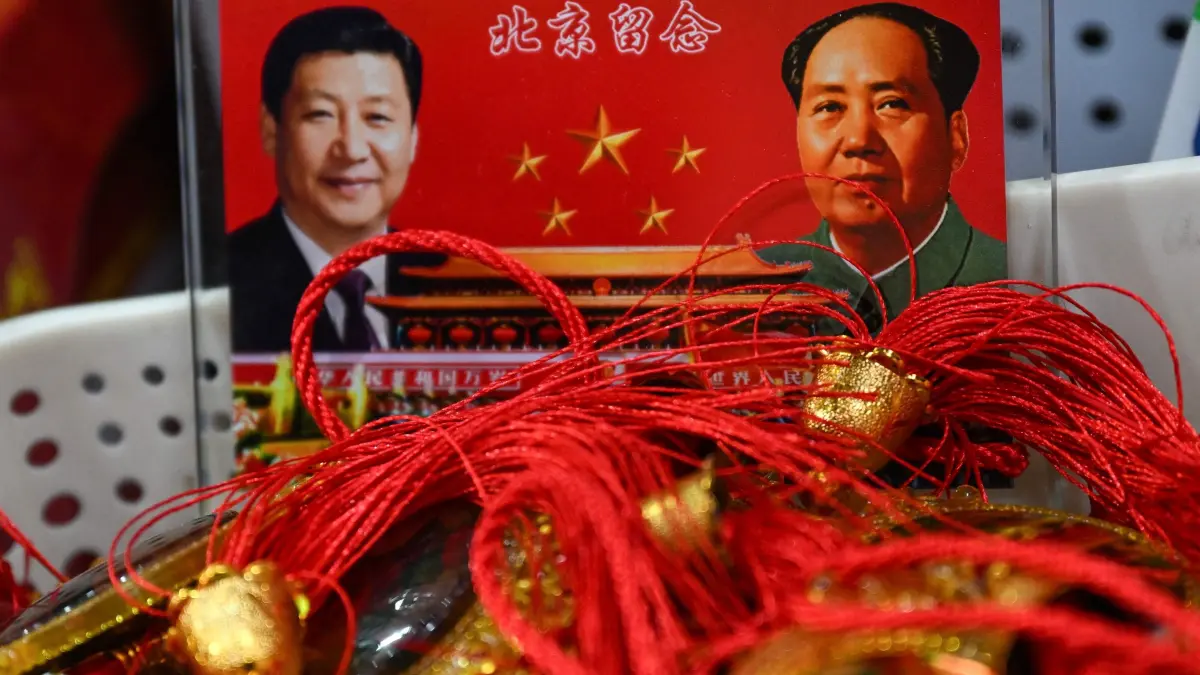 Portraits of China's President Xi Jinping (L) and late communist leader Mao Zedong are seen at a souvenir shop in a tourist area of Beijing on March 4, 2026. (Photo by Pedro PARDO / AFP)