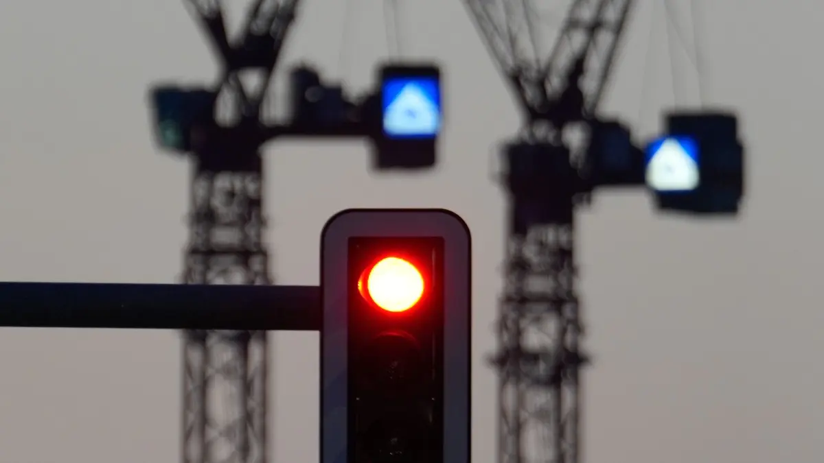 Baustelle: ARCHIV - 27.02.2026, Berlin: Eine Ampel zeigt vor der Kulisse von zwei Baukranen rotes Licht. (zu dpa: «Institute dürften Konjunkturprognose senken») Foto: Soeren Stache/dpa +++ dpa-Bildfunk +++