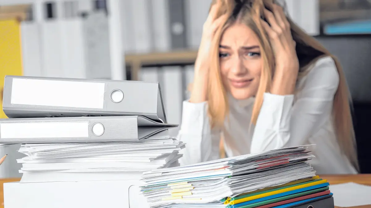 Emotional woman with stack of documents on her table in office