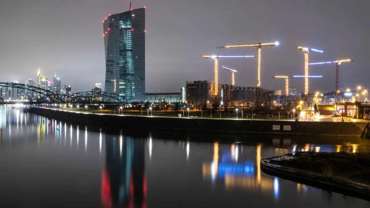 EZB in Frankfurt am Main: ACHTUNG: SPERRFRIST 8. APRIL 17:00 UHR. ACHTUNG: DIESER BEITRAG DARF NICHT VOR DER SPERRFRIST, 8. APRIL, 17.00 UHR, VERÖFFENTLICHT WERDEN! EIN BRUCH DES EMBARGOS KÖNNTE DIE BERICHTERSTATTUNG ÜBER STUDIEN EMPFINDLICH EINSCHRÄNKEN. - ARCHIV - 03.01.2021, Hessen, Frankfurt/Main: Die Hochhäuser der Bankenskyline von Frankfurt ragen hinter der Europäischen Zentralbank (EZB) aus der hereinbrechenden Dunkelheit empor. Rechts im Bild stehen die beleuchteten Baukräne einer Großbaustelle. (Zu dpa "Aufseher prüfen Widerstandsfähigkeit von Europas Banken") (zu dpa: «Künstliche Beleuchtung hat weltweit stark zugenommen») Foto: Boris Roessler/dpa +++ dpa-Bildfunk +++