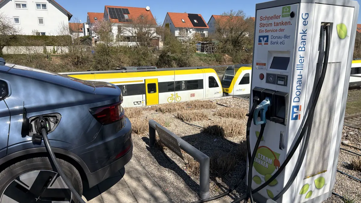 Alternativen zum teuren Sprit: Eine Stromtankstelle in der Nähe des Ehinger Bahnhofs, im Hintergrund fährt gerade ein Zug ein.