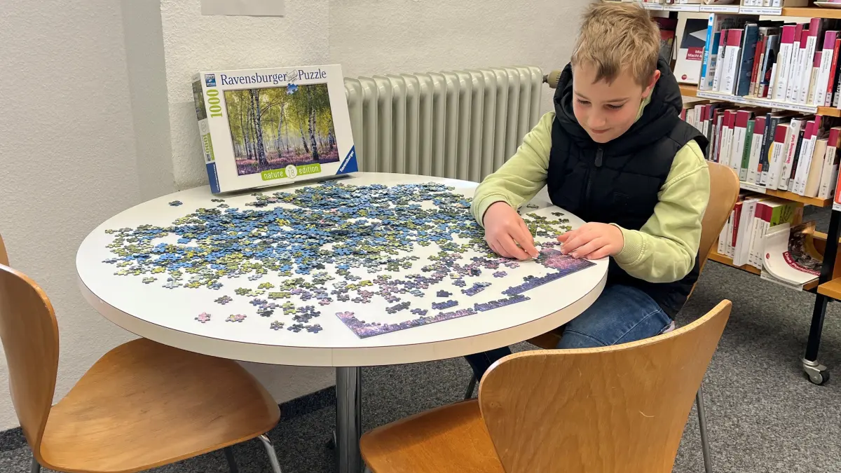 Ein Junge versucht sich an dem 1000-Teile-Puzzle, welches in den Ostreferien als Aktion in der Gaildorfer Stadtbücherei ausliegt.