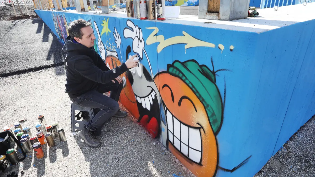 Marco Neumann sprayt Graffiti an die Wand auf dem Spiel- und Sportplatz im Anlagenpark