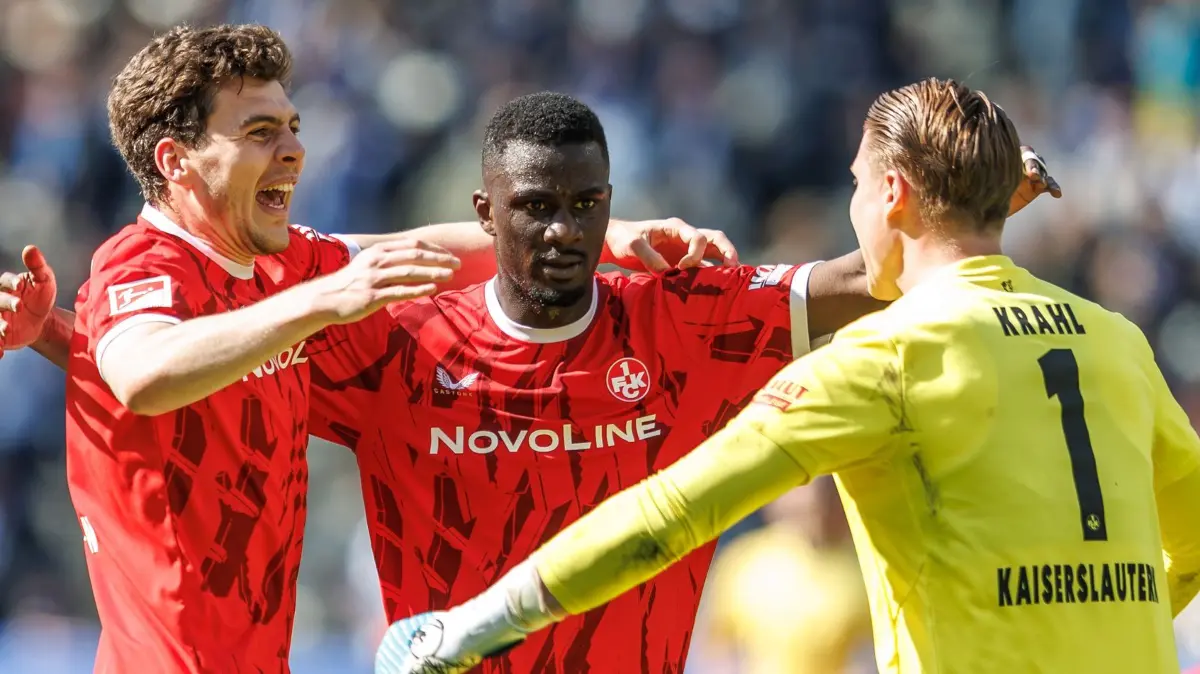 Hertha BSC - 1. FC Kaiserslautern: 11.04.2026, Berlin: Fußball, Männer: 2. Bundesliga, Hertha BSC - 1. FC Kaiserslautern, 29. Spieltag, Olympiastadion. Jacob Rasmussen (l, 1. FC Kaiserslautern), Maxwell Gyamfi (M, 1. FC Kaiserslautern) und Julian Krahl (r, 1. FC Kaiserslautern) freuen sich nach dem Schlusspfiff über den Sieg. Foto: Andreas Gora/dpa - WICHTIGER HINWEIS: Gemäß den Vorgaben der DFL Deutsche Fußball Liga bzw. des DFB Deutscher Fußball-Bund ist es untersagt, in dem Stadion und/oder vom Spiel angefertigte Fotoaufnahmen in Form von Sequenzbildern und/oder videoähnlichen Fotostrecken zu verwerten bzw. verwerten zu lassen. +++ dpa-Bildfunk +++