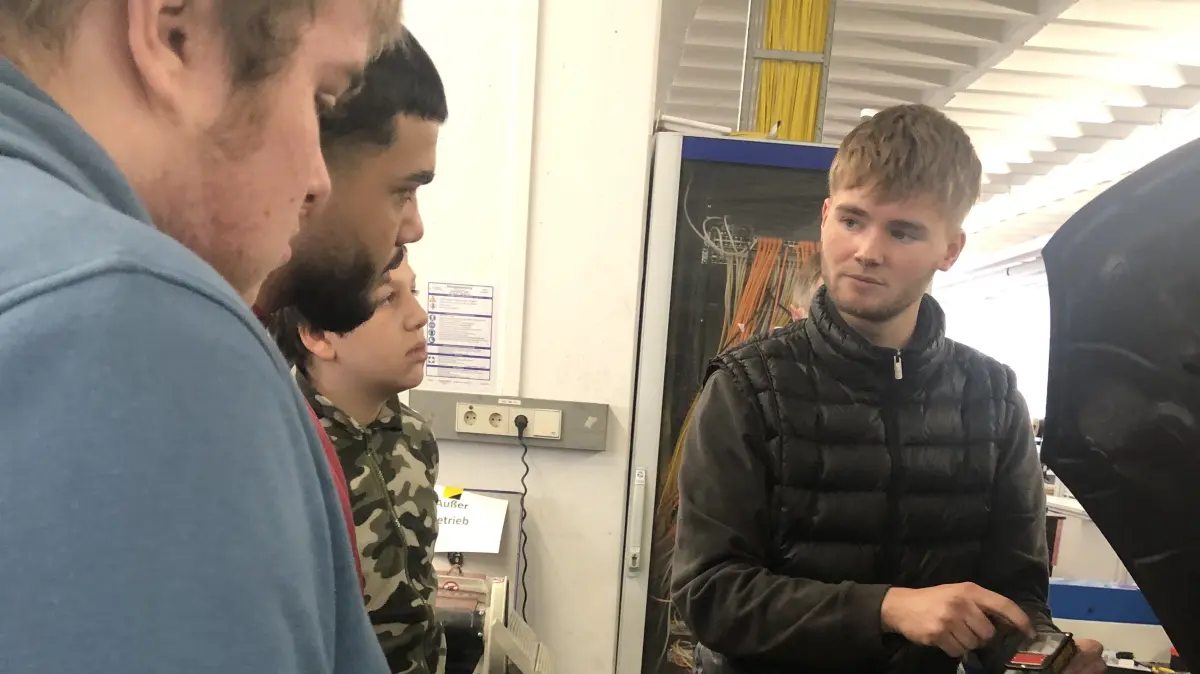Maurice Bendrin erklärt bei der ABA in Albstadt Schülern von der Ausbildung zum Kfz-Mechatroniker.