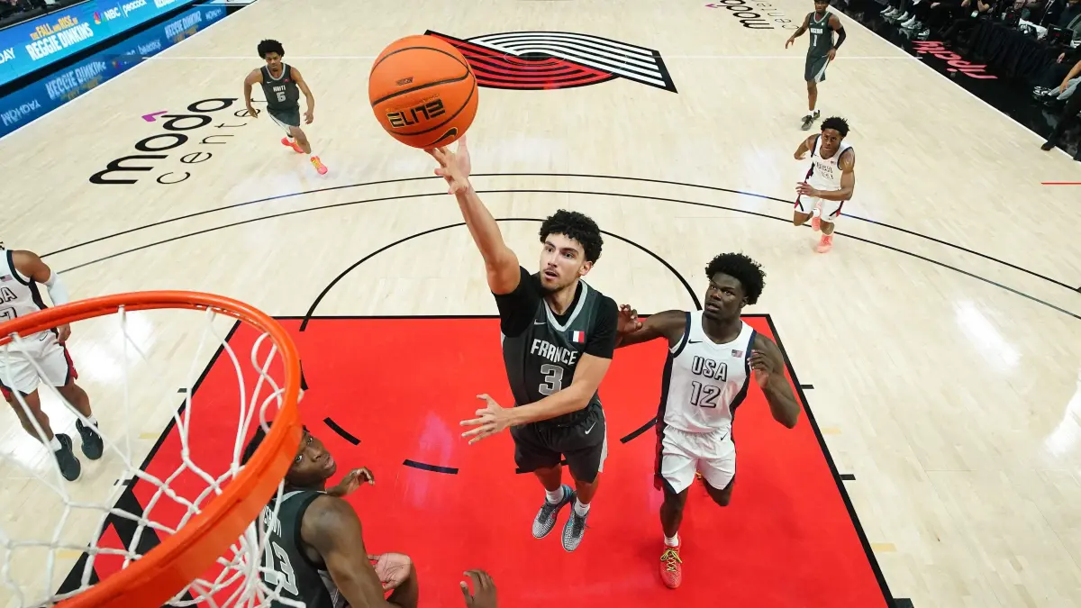 2026 Nike Hoop Summit: PORTLAND, OREGON - APRIL 11: Adam Atamna #3 of the Team World goes up for a shot against Caleb Gaskins #12 of the Team USA during the first half at Moda Center on April 11, 2026 in Portland, Oregon. Soobum Im/Getty Images/AFP (Photo by Soobum Im / GETTY IMAGES NORTH AMERICA / Getty Images via AFP)