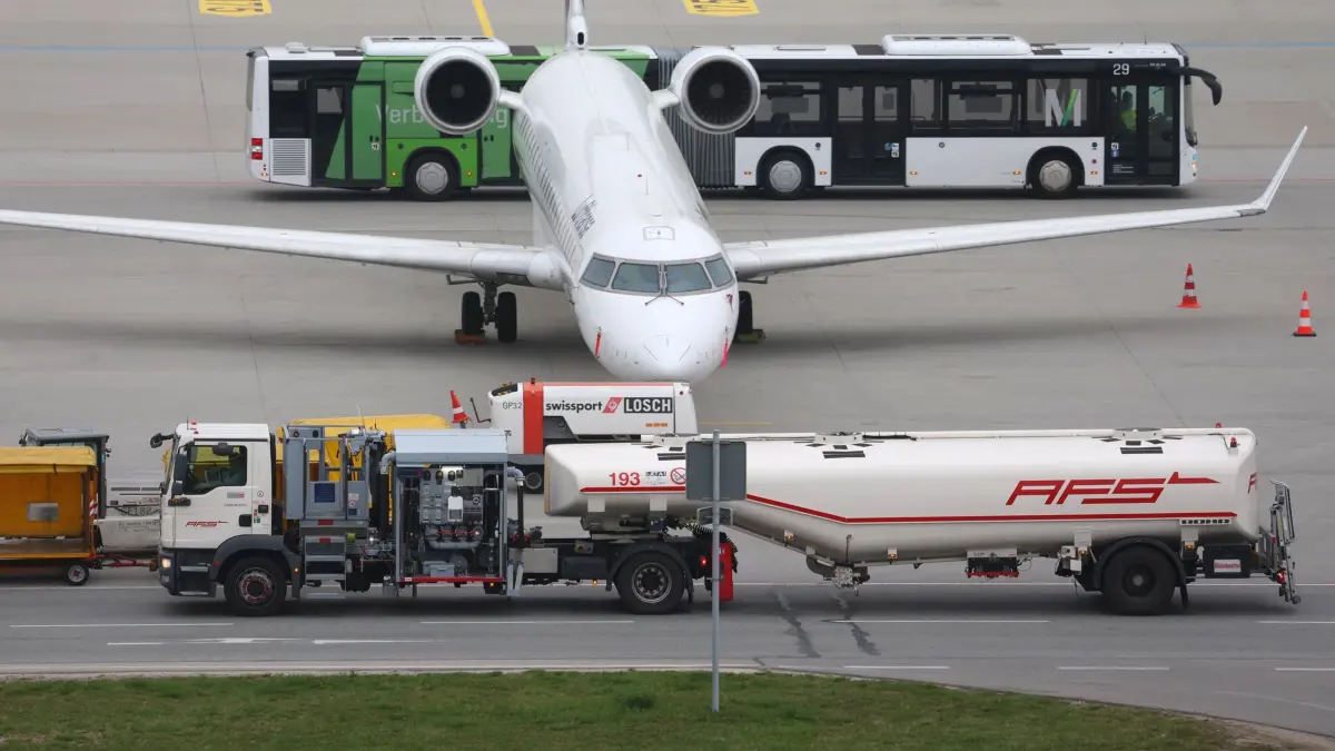 Flugzeugbetankung am Flughafen: 14.04.2026, Bayern, München: Ein Tankfahrzeug (vorne) fährt auf dem Vorfeld des Flughafens München an einem Passagierflugzeug vorbei. Der Preis für Kerosin gilt als zentraler Kostenfaktor im Luftverkehr und beeinflusst unter anderem Ticketpreise und wirtschaftliche Ergebnisse von Fluggesellschaften. (zu dpa: «Iran-Krieg: Europas Fluglinien fordern Notfallmaßnahmen») Foto: Karl-Josef Hildenbrand/dpa +++ dpa-Bildfunk +++