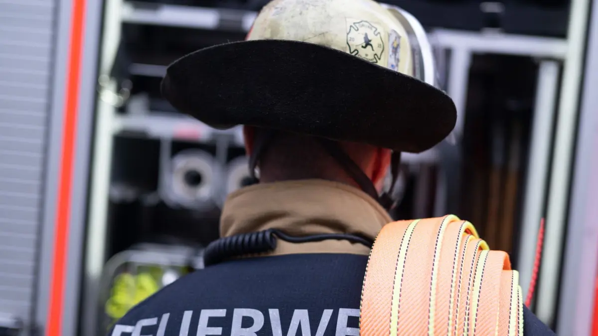 Feuerwehr: ARCHIV - 12.02.2025, Baden-Württemberg, Stuttgart: Eine Einsatzkraft der Feuerwehr steht im Hof der Feuerwache 5 Filder vor einem Einsatzfahrzeug (gestellte Szene). (zu dpa: «Bewohner nach Brandstiftung in Haft») Foto: Marijan Murat/dpa +++ dpa-Bildfunk +++