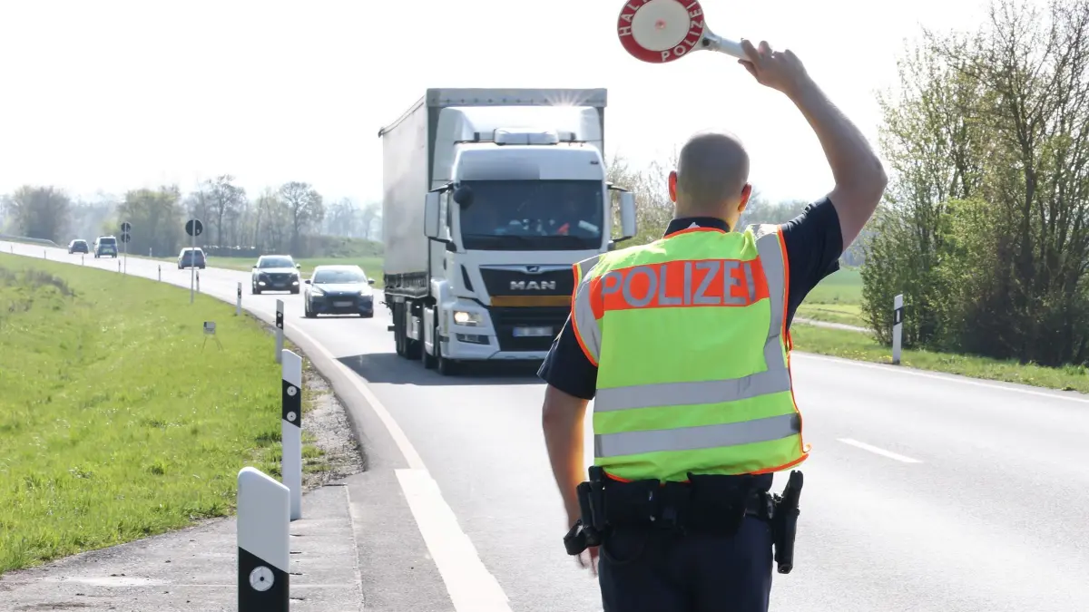 Blitzermarathon - Bayern: 15.04.2026, Bayern, Sulzheim-Alitzheim: Beim bayernweiten Blitzermarathon winkt ein Polizeibeamter der PI Gerolzhofen an der B286 an einem Parkplatz mit der Polizeikelle einen Lastwagen zur Kontrolle raus. Foto: Daniel Löb/dpa - ACHTUNG: Kennzeichen wurde(n) aus rechtlichen Gründen gepixelt +++ dpa-Bildfunk +++